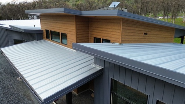 Modern home with sleek metal roofing, dark siding, and warm wood accents.