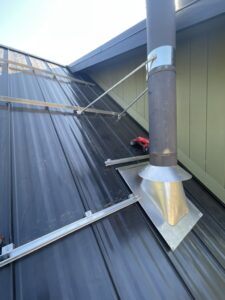 Standing seam metal roof with custom chimney flashing and professionally installed snow retention system.